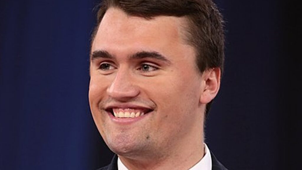 Close-up of Charlie Kirk smiling during a debate, showcasing symmetrical white teeth and dental aesthetics.