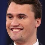 Close-up of Charlie Kirk smiling during a debate, showcasing symmetrical white teeth and dental aesthetics.